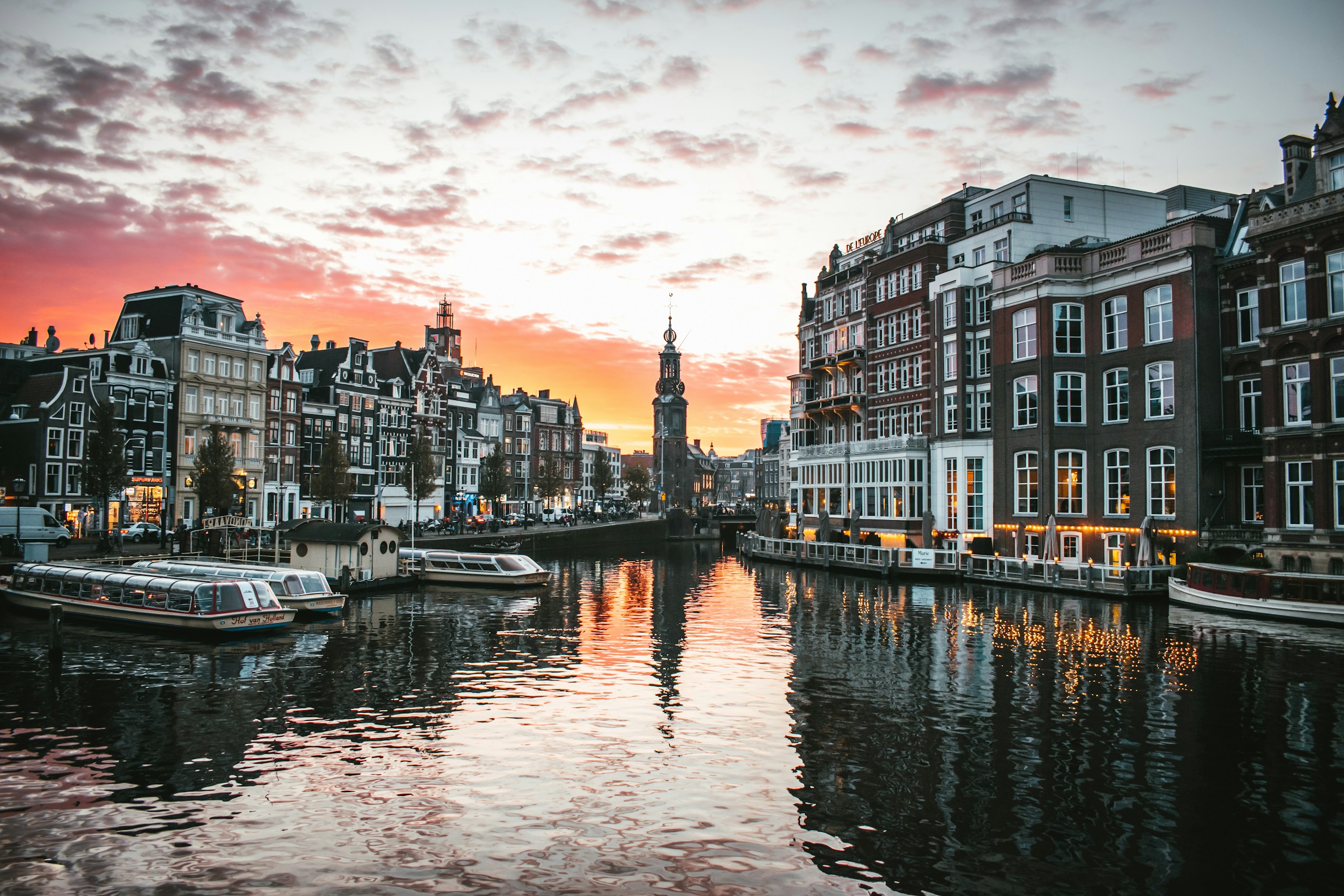 Sfeerbeeld van Amsterdamse stadsarchitectuur aan het water bij zonsondergang