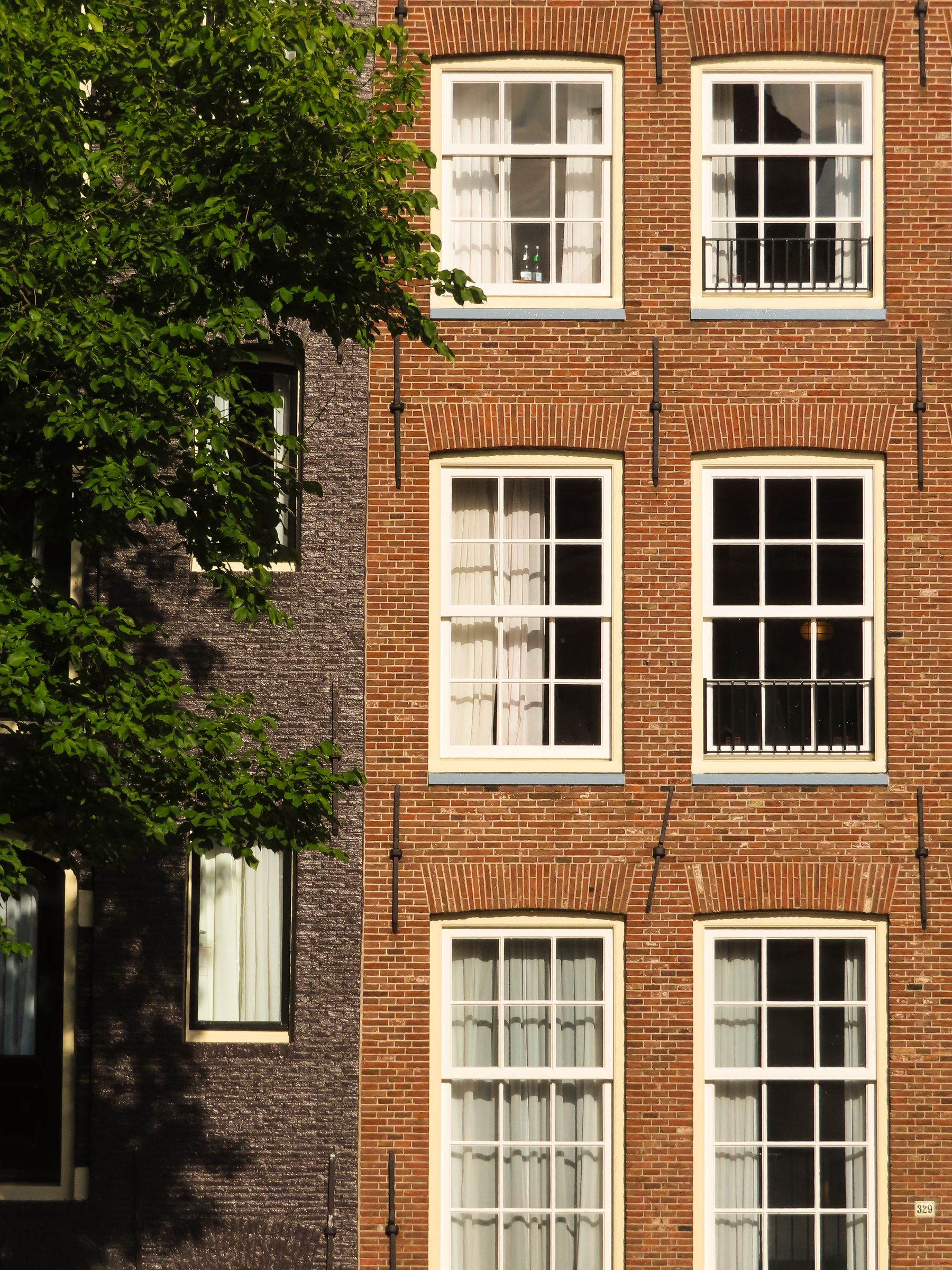 Sfeerbeeld: zonlicht en schaduw op Amsterdamse bakstenen gevels